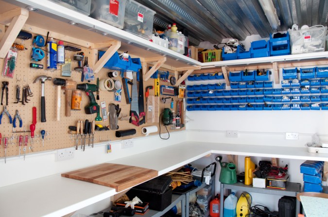 Garaje con estantes de madera y herramientas en pared ordenada.