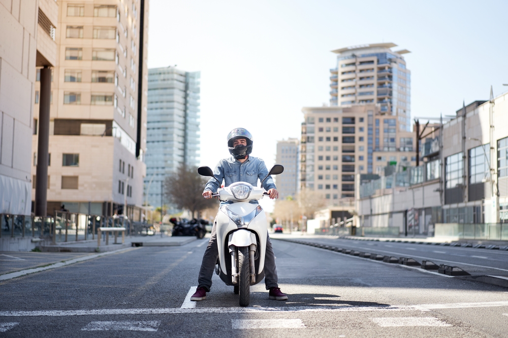 Motocicleta blanca en calle urbana con casco, optimizando consumo de combustible en ciudad.