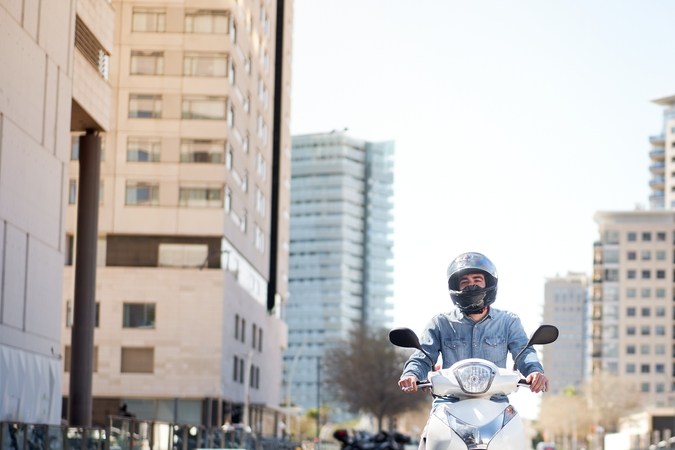 Motocicleta blanca en calle urbana con casco, optimizando consumo de combustible en ciudad.