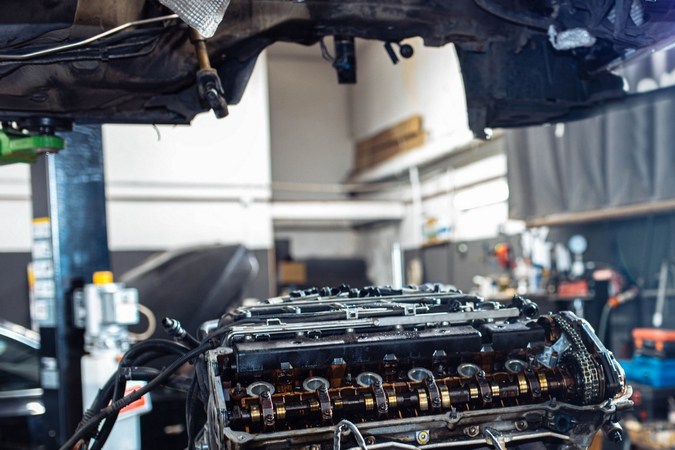 Motor en taller con culata expuesta, útil para reparar humo del tapón de aceite y mantenimiento automotriz.