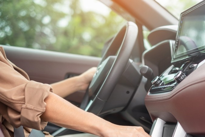 Mano de mujer cambiando palanca de auto automático, interior moderno con pantalla.