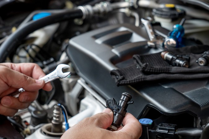 Manos trabajando en motor de coche, overhaul automotriz, reparación de piezas en taller mecánico.