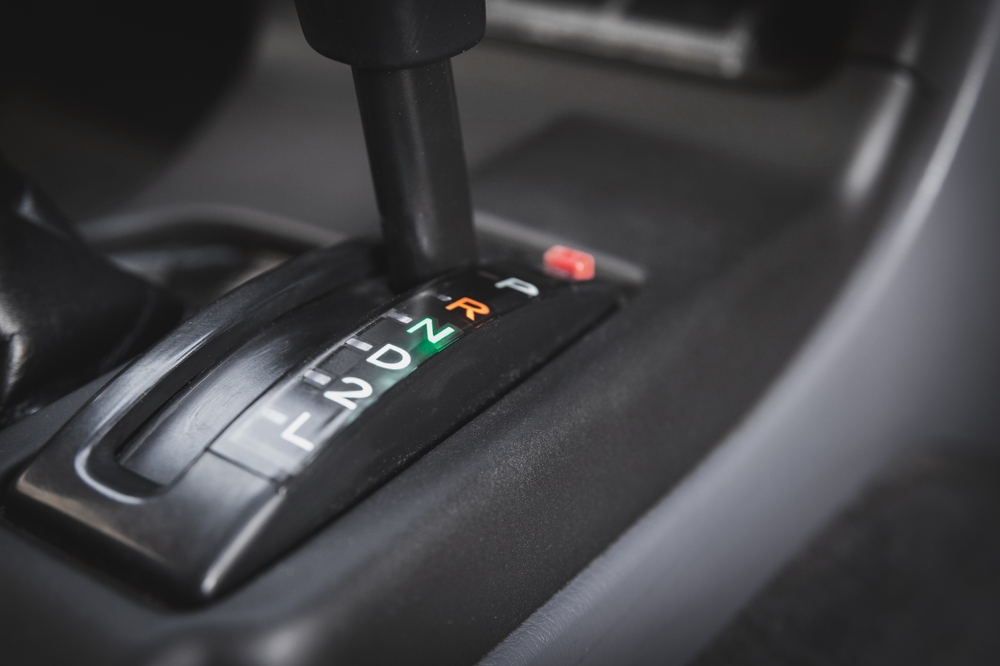 Palanca de cambios automática en posición R iluminada, detalle interior de auto.