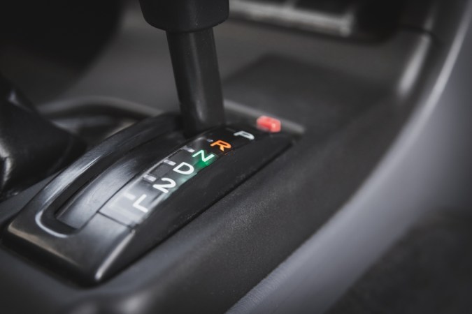 Palanca de cambios automática en posición R iluminada, detalle interior de auto.