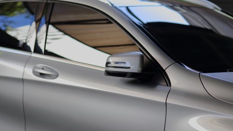 Auto gris con polarizado en ventanas, reflejando naturaleza, ideal para protección solar y diseño moderno.
