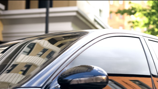 Auto con polarizado oscuro en ventanas, reflejando entorno urbano, ideal para privacidad y estilo.
