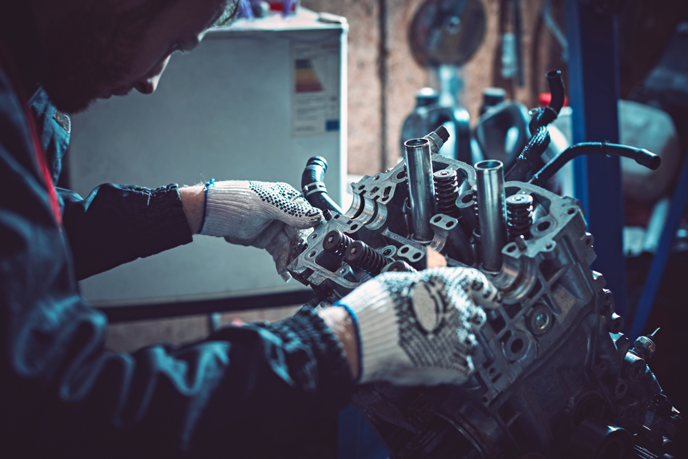 Mecánico trabajando en un motor durante overhaul, reparación de coche en taller, mantenimiento automotriz profesional.