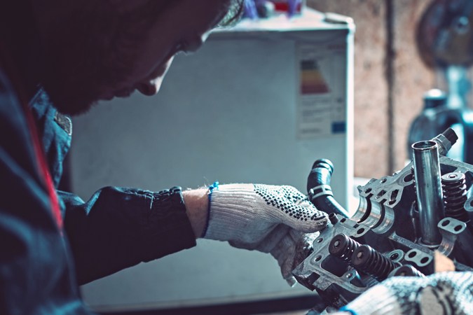 Mecánico trabajando en un motor durante overhaul, reparación de coche en taller, mantenimiento automotriz profesional.