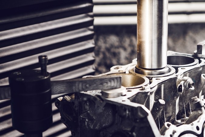 Motor abierto en taller con pistones visibles, proceso de overhaul automotriz, reparación de componentes internos.