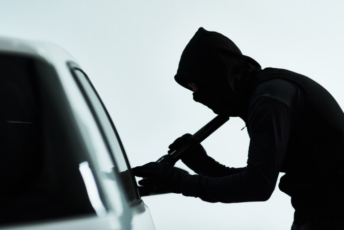 Hombre, coche y robo intento con criminal, automóvil y luz de destello o comprobar la posesión valiosa en el interior. Ilícito, evaluar vehículo y seguridad para sistema antirrobo, encapuchado y estacionamiento