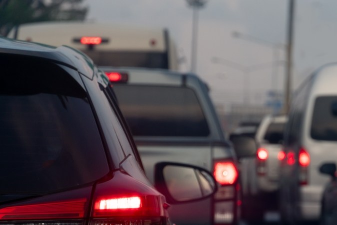 Fila de autos en un trancon urbano, con luces rojas de freno iluminadas y una carretera congestionada.