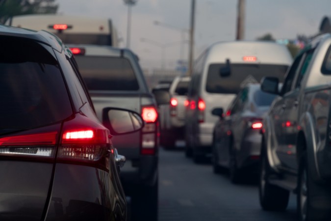 Fila de autos en un trancon urbano, con luces rojas de freno iluminadas y una carretera congestionada.