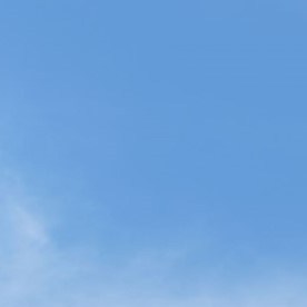 Dos sedanes Toyota Camry 2026, uno gris y otro azul, estacionados en una plaza adoquinada con árboles, quiosco y banderines bajo cielo despejado.