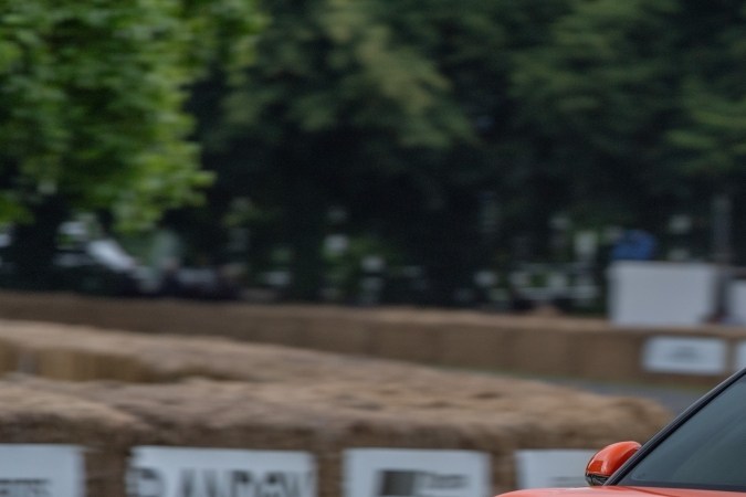 Genesis GV60 Magma Concept compitiendo en Goodwood, SUV eléctrico performance con detalles deportivos, color naranja y aerodinámica avanzada.