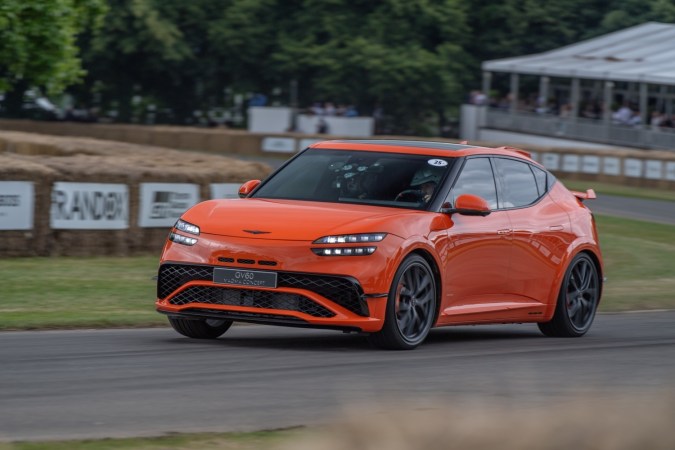 Genesis GV60 Magma Concept compitiendo en Goodwood, SUV eléctrico performance con detalles deportivos, color naranja y aerodinámica avanzada.