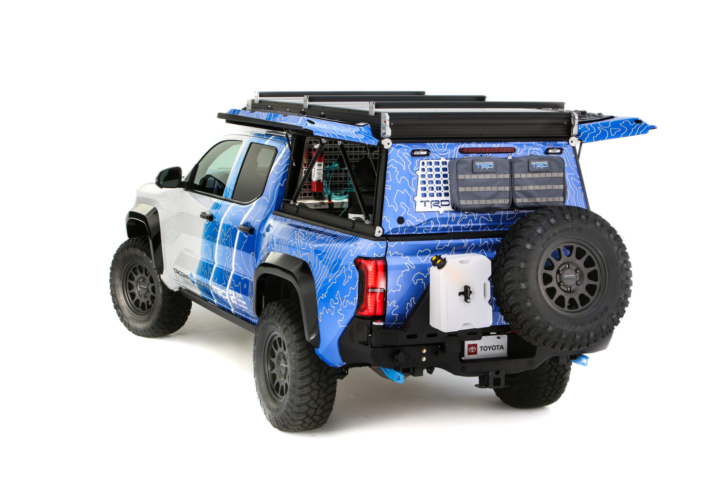 Parte trasera Toyota Tacoma H2 Overlander cerrada: Vista trasera de la Toyota Tacoma H2 Overlander con accesorios todoterreno y compartimientos de carga cerrados.
