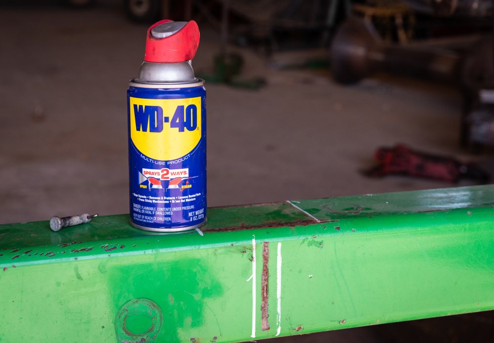 Una foto de una lata de WD-40 en un granero sobre una barra metálica verde.