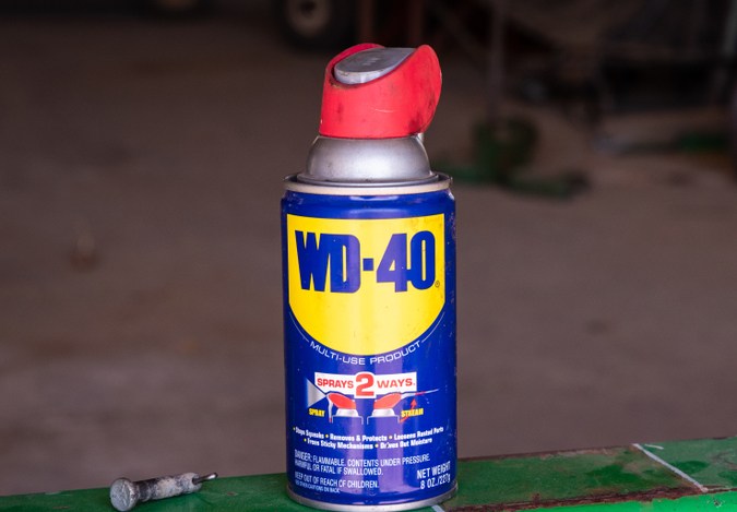 Una foto de una lata de WD-40 en un granero sobre una barra metálica verde.