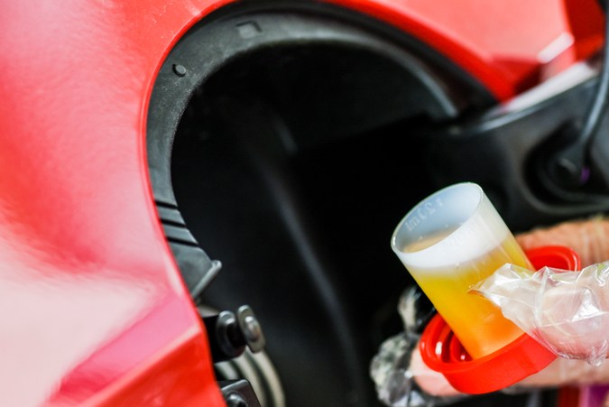 Vierte líquido aditivo en el depósito del coche. Mantenimiento para un uso prolongado sin reparación. Fluido adicional para gasolina