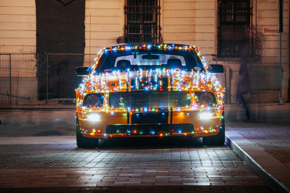 Ford Mustang en el centro de la ciudad con decoraciones de luces navideñas.