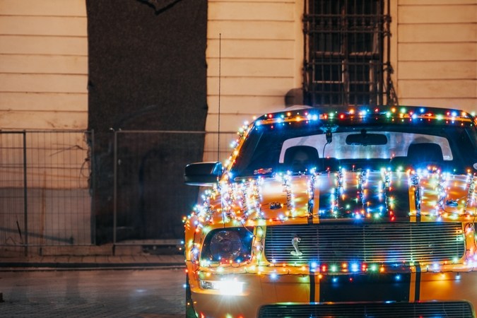 Ford Mustang en el centro de la ciudad con decoraciones de luces navideñas.