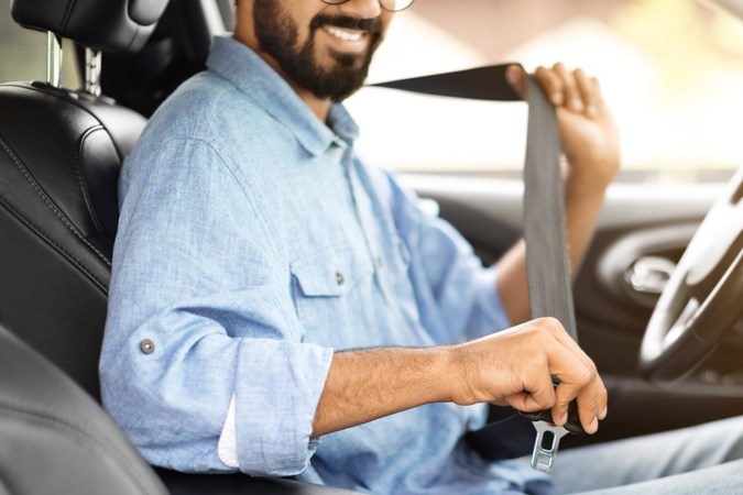 Persona abrochándose el cinturón de seguridad correctamente en el asiento del conductor.