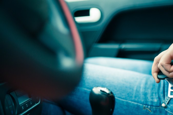 Manos ajustando el cinturón de seguridad en un automóvil moderno.