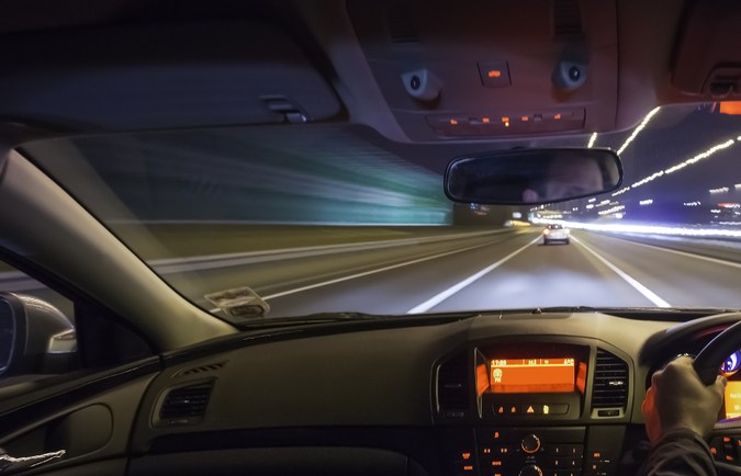 Conducir rápido después de un coche en autopista por la noche.