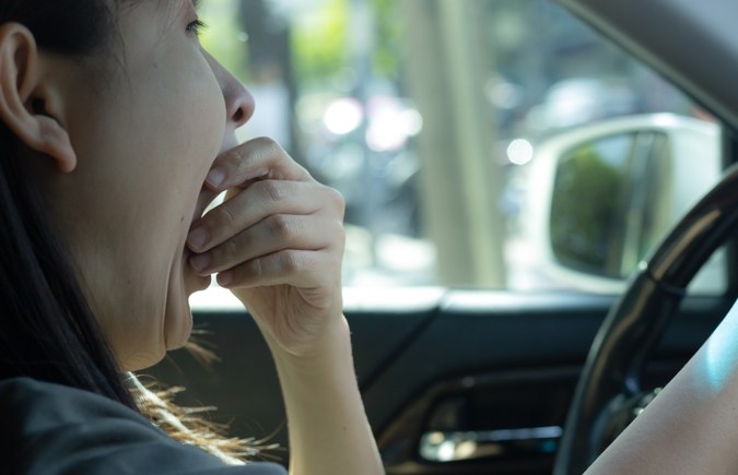 Mujer somnolienta mientras conducía por la carretera. Concepto de salud y seguridad en la conducción. Mujer con sueño bostezando. Una mujer conduce un auto con mal atasco en hora punta. somnoliento mientras conduce. accidente de carretera