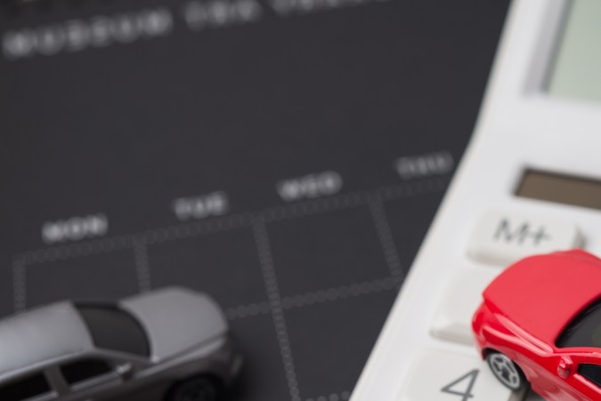 Toy cars model, black calendar and white calculator. Money financial management and calculation for buying car, car leasing, down payment, installment, auto insurance, service costs and so on concept.