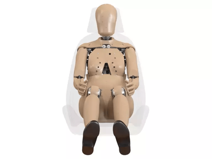 Vista frontal de crash test dummy femenino en asiento, usado para pruebas de impacto y desarrollo de autos más seguros para mujeres conductoras y pasajeras.