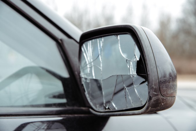 Retrovisor roto del coche. El espejo del coche está dañado, cristales rotos. Concepto de accidente, colisión de tráfico. Daños en el retrovisor lateral, mala conducción, problemas con el coche.