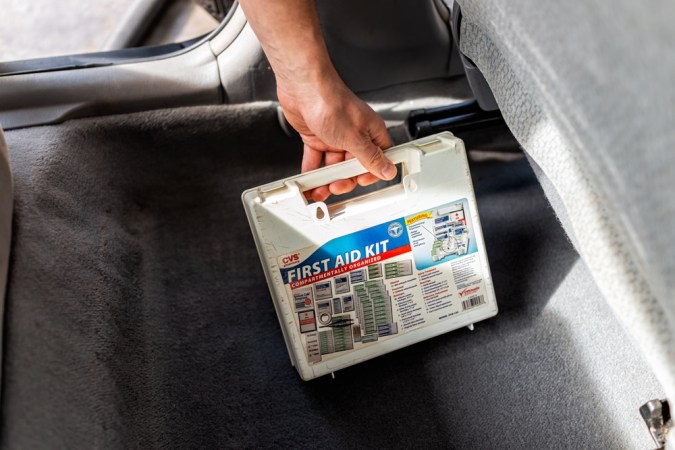 Kit de primeros auxilios, mano con suministros médicos de emergencia en el interior del auto por asiento del vehículo para atención urgente de viajes