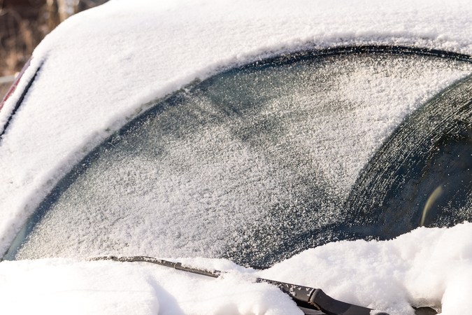 Pesada nieve cayó sobre el parabrisas de un auto durante el invierno