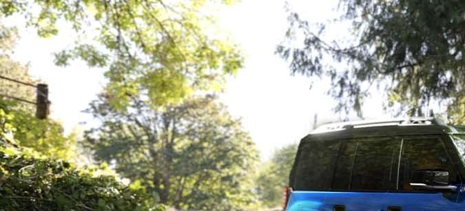 Jeep Recon 2026 azul cruzando agua, demostrando resistencia y tecnología 4x4 eléctrica en entorno natural forestal.