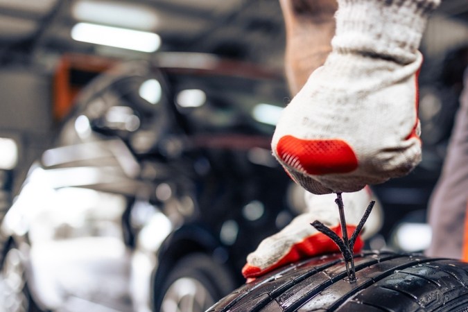 Reemplazo del neumático dañado. Vista de cerca del reparador usando el kit de reparación de neumáticos para reparar el neumático dañado.