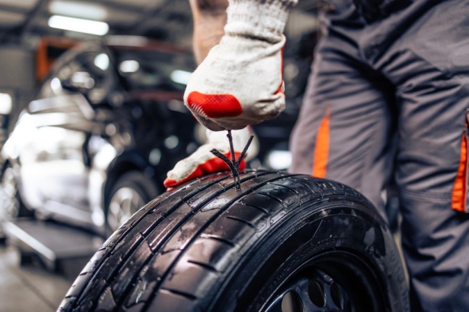 Reemplazo del neumático dañado. Vista de cerca del reparador usando el kit de reparación de neumáticos para reparar el neumático dañado.