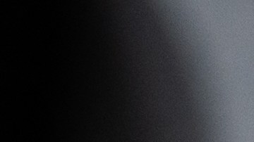 La mano de la persona se moja lijando un faro de coche para la restauración, pegado con cinta adhesiva verde.