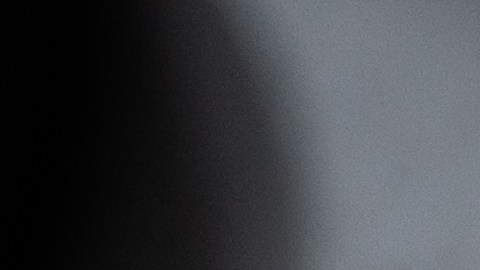 La mano de la persona se moja lijando un faro de coche para la restauración, pegado con cinta adhesiva verde.