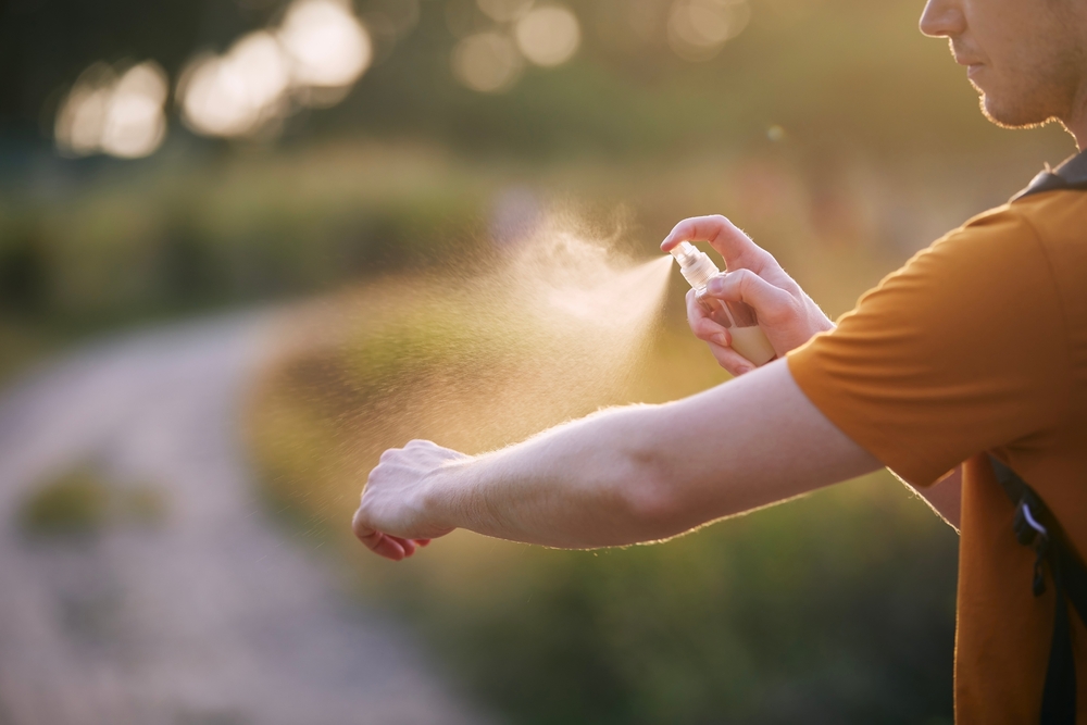 Prevención contra la picadura de mosquitos en destino tropical. Hombre aplicando repelente de insectos en su mano.