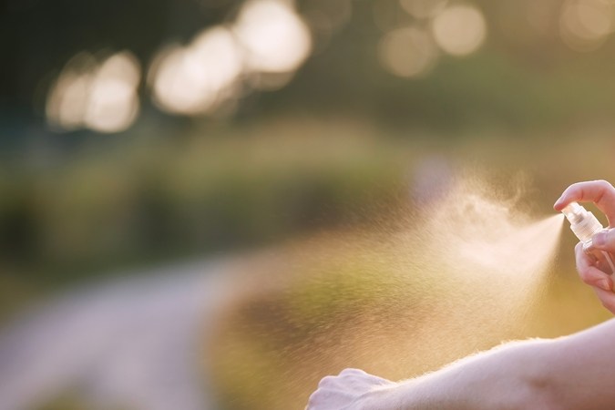 Prevención contra la picadura de mosquitos en destino tropical. Hombre aplicando repelente de insectos en su mano.