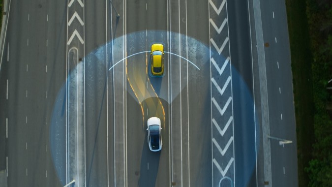 Vista aérea arriba abajo: Auto Autónomo Autoconducido Que Se Mueve Por La Ciudad, Pasando Por Otros Vehículos.