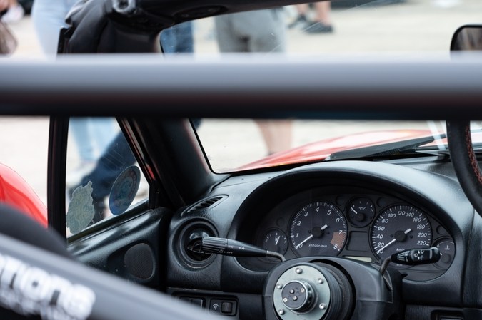 Un primer plano de la cabina interior de un clásico Mazda Miata NB. El deportivo JDM se ha modificado con un volante de Autorización rápida y una barra antivuelco con especificaciones de carrera