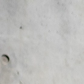 Vista tres cuartos del Nissan Versa 2025 rojo frente a arquitectura moderna, exhibiendo el diseño exterior renovado de este auto económico descontinuado.