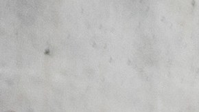 Vista tres cuartos del Nissan Versa 2025 rojo frente a arquitectura moderna, exhibiendo el diseño exterior renovado de este auto económico descontinuado.