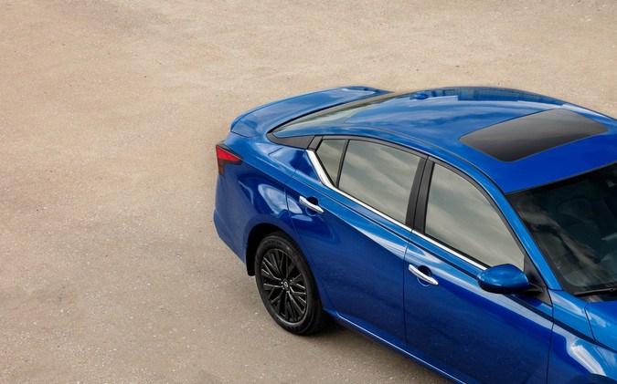 Nissan Altima azul 2025 visto desde arriba con techo panorámico, llantas negras y diseño deportivo estacionado sobre superficie clara.