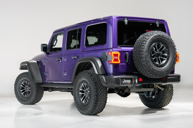 Jeep Wrangler Moab 2026 morado, todoterreno 4x4, edición especial aniversario, vista trasera lateral en estudio, neumáticos off-road grandes.