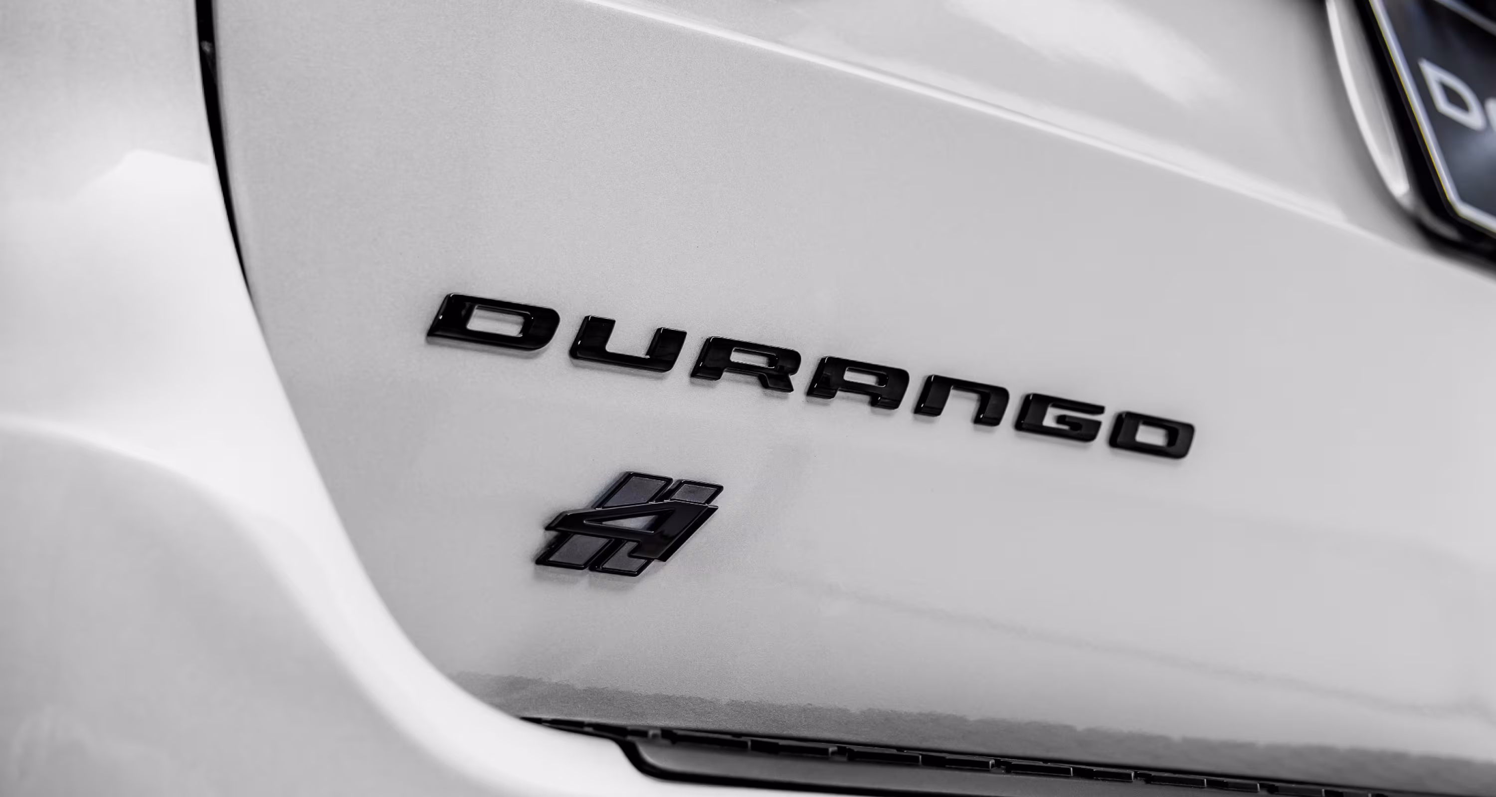Primer plano del emblema trasero negro Dodge Durango SRT Hellcat 4 en carrocería blanca, resaltando detalles exclusivos del modelo 2026.