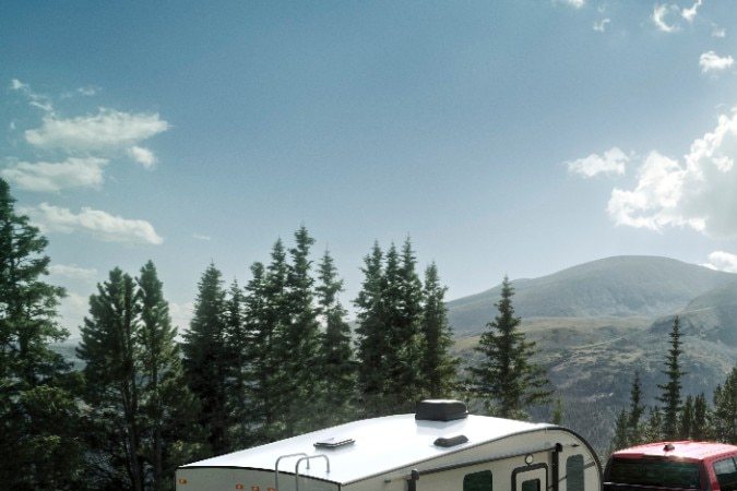 Pick-up Ford Maverick 2026 roja remolcando casa rodante en camino de montaña, demostrando capacidad de arrastre, aventura y desempeño todoterreno.