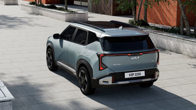 SUV Kia Seltos 2027 azul visto desde atrás, diseño cuadrado, luces LED unidas y techo panorámico, estacionado en entorno urbano moderno.